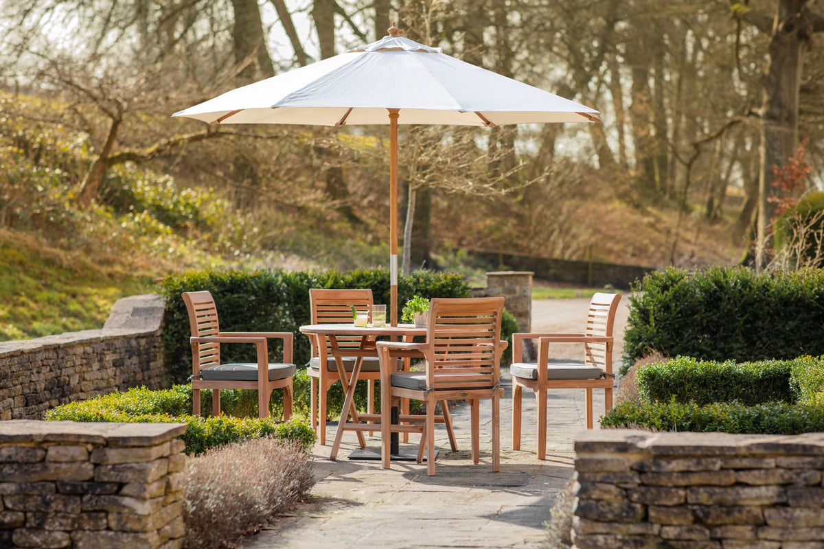 Outdoor patio setting with wooden furniture and umbrella in a garden.